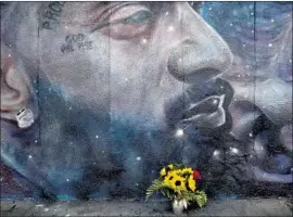  ?? Luis Sinco Los Angeles Times ?? FLOWERS LIE at the base of a mural of Nipsey Hussle on Crenshaw Boulevard. The L.A. murals are a testament to Hussle’s legacy as a musician and activist.