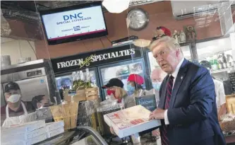  ?? BRENDAN SMIALOWSKI/AFP VIA GETTY IMAGES ?? President Donald Trump picks up a pizza at Arcaro and Genell in Old Forge, Pennsylvan­ia, during a campaign stop on Thursday.