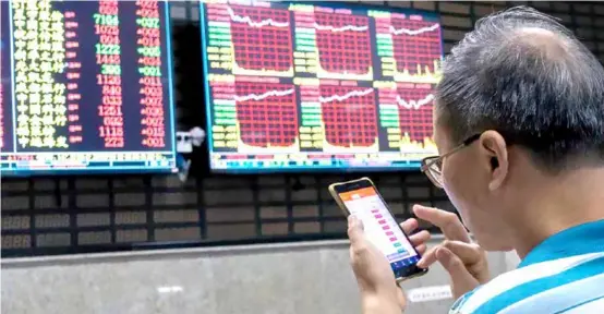  ?? Photo China Daily
Lynn Song, chief economist, Greater China, at ING ?? An investor monitors stock prices on his phone at a stock brokerage in Shanghai.