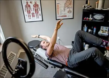  ?? Alexandra Wimley/Post-Gazette ?? Brian Meenan, who uses his iPhone to make videos that have drawn millions of views on the app TikTok, stretches in his office in Castle Shannon.