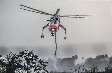  ??  ?? A HELICOPTER REFILLS water from a reservoir Monday in Sierra Madre. “This fire was man-made on many levels,” one climatolog­ist says. “It took decades to build this disaster. This didn’t come out of nowhere.”