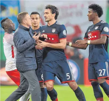  ?? FOTO: IMAGO ?? Pokalkampf einmal anders: Leipzigs Sportdirek­tor Ralf Rangnick zückt sein Smartphone, Bayerns Mats Hummels ist gar nicht begeistert und will ihn blocken.