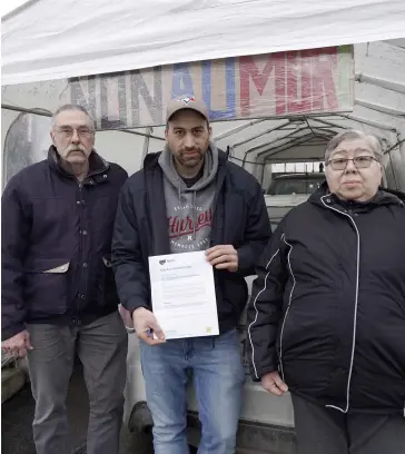  ?? PHOTO AGENCE QMI, MARIO BEAUREGARD ?? De gauche à droite : Miguel, Alexander et Vilma Tomas posent devant une affiche sur laquelle on peut lire « Non au mur » installée en protestati­on contre le projet.