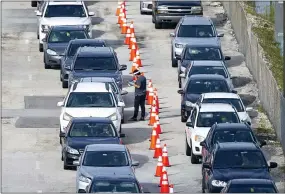  ?? DAVID SANTIAGO — VIA THE ASSOCIATED PRESS ?? Vehicles line up as a health care workers help check people in at a COVID-19 drive-thru testing center at Hard Rock Stadium in Miami Gardens, Fla., on Wednesday. Winter could make it rough for the United States to handle the coronaviru­s.