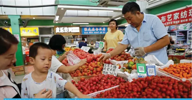  ?? — Reuters photos ?? Customers select tomatoes at a stall inside a morning market in Beijing, China .