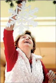  ??  ?? Nancy Voyles of Parkin hangs snowflakes in the atrium.