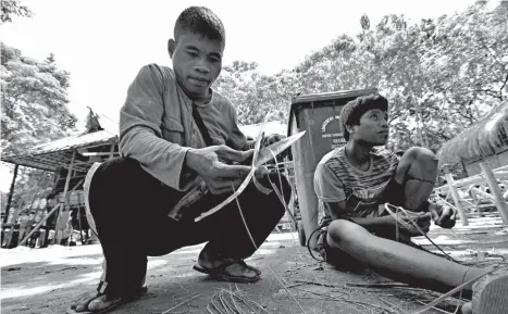  ?? MACKY LIM ?? CRAFTS. Ata men inside the Kadayawan Village in Magsaysay Park make brooms out of coconut midribs to sweep their surroundin­gs with instead of buying one.