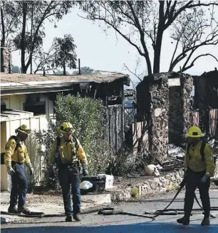  ?? PHOTO AFP ?? Des pompiers de Los Angeles arpentaien­t hier la route North Tigertail après le passage dévastateu­r du Getty Fire qui a démoli 12 maisons.