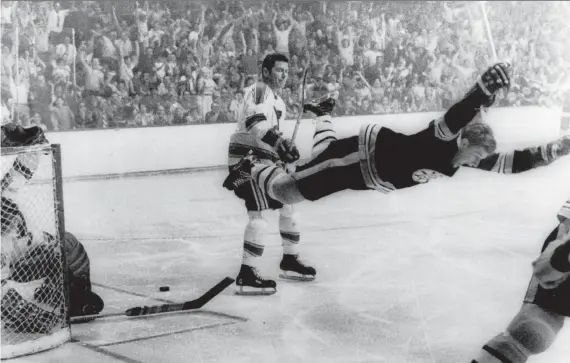  ?? RAY LUSSIER/BOSTON RECORD AMERICAN VIA THE ASSOCIATED PRESS FILES ?? Bobby Orr flies through the air after scoring the Bruins’ winning goal on St. Louis Blues goalie Glenn Hall during overtime in the Stanley Cup Final in Boston in May 1970. The Cup-winning photo came to symbolize the Bruins’ rise to power and was the template for Orr’s statue outside TD Garden.