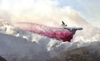  ?? AP ?? A firefighti­ng DC-10 makes a fire retardant drop over a wildfire in the mountains near Malibu Canyon Road in Malibu, California on Sunday.