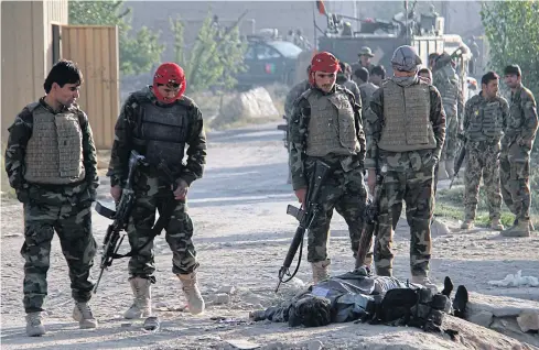  ?? EPA ?? Afghan soldiers stand beside the body of one of the Taliban militants after an attack on a prison in Ghazni, Afghanista­n yesterday. At least four police officers were killed when Taliban militants stormed a prison in Ghazni, freeing more than 350...