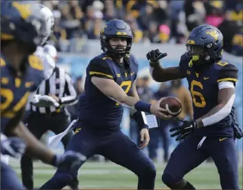  ?? Ray Thompson/The Associated Press ?? West Virginia QB Will Grier, center, hands off to running back Kennedy McKoy in a 47-10 win Saturday against TCU. The Mountainee­rs are atop the Big 12 standings with two games left.