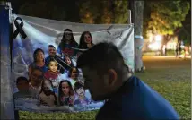  ?? JAE C. HONG/ASSOCIATED PRESS ?? A man, who declined to give his name, sits Tuesday in front of a banner of victims’ images who were killed in last week’s elementary school shooting in Uvalde, Texas.