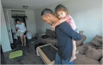  ??  ?? Byron Soto, 31, carries his daughter, Kiara, inside their flooded apartment. The family evacuated to an empty upstairs unit.
