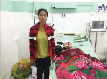  ?? DAPHNE CHEN ?? Khet Pos, 25, stands next to her husband, Mroeum Di, 29, who is being treated at Khmer-Soviet Friendship Hospital after he was shot in the head for allegedly practising sorcery.