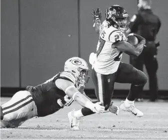  ??  ?? Texans running back Scottie Phillips tries to elude but is tripped up by Packers defensive tackle Jack Heflin during the second quarter. Phillips scored a touchdown during the quarter.