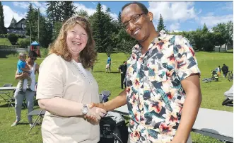  ?? JIM WELLS ?? Neighbours Jodie Wiede, left, and Daniel Asfeday shake hands and share a laugh during the Sunalta community’s Neighbour Day event. The pair were forced from their homes following a recent fire that levelled their apartment building. About his...