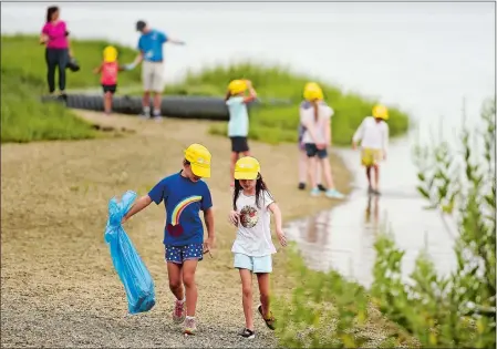  ?? SEAN D. ELLIOT/THE DAY ?? Summer campers from Mystic Aquarium pick up trash along the trail at Bluff Point State Park in Groton on Wednesday as part of a social media campaign to raise awareness of the impacts of plastics on Long Island Sound wildlife. The seven-week campaign,...