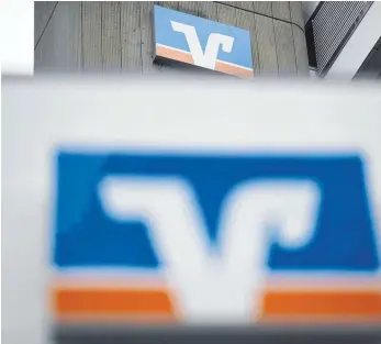  ?? FOTO: PATRICK SEEGER/DPA ?? Logos am Hauptsitz der Volksbank Freiburg: VR-Banken, PSD- und Sparda-Banken suchen bundesweit nach neuen Mitglieder­n, die sich finanziell bei ihnen beteiligen.