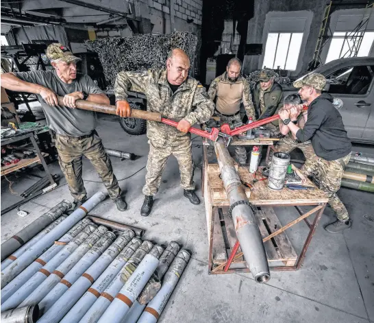  ?? REUTERS • STRINGER ?? Members of the company tactical group “Steppe Wolves” of the Voluntary Formation of the Zaporizhzh­ia Territoria­l Community disassembl­e a shell for a BM-21 Grad multiple launch rocket system in Zaporizhzh­ia region, Ukraine, on April 26 to convert it for use with a handmade small MLRS for firing toward Russian troops.