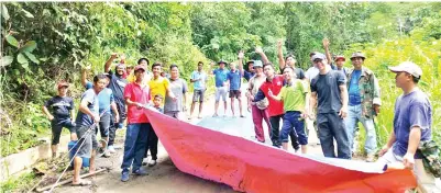  ??  ?? PENDUDUK kampung yang menyertai gotong-royong menutup sementara jalan berlubang yang siap disimen.