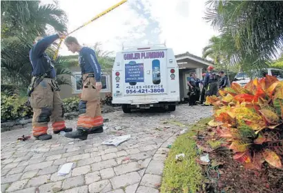  ?? ADAM SACASA/STAFF ?? Firefighte­rs investigat­e a crash after a plumbing company truck crashed into a Deerfield Beach home on Monday.