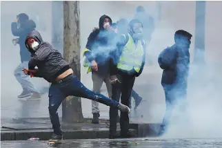  ?? REUTERS ?? PROTESTERS wearing yellow vests react as French police fire tear gas during a demonstrat­ion of the ‘yellow vests’ movement in Paris in Dec. 15 photo.