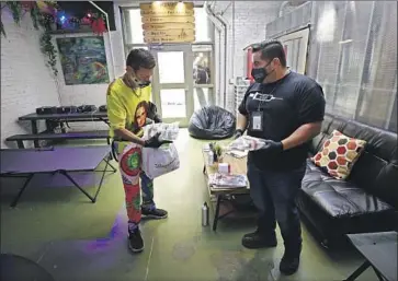  ?? Photograph­s by Al Seib Los Angeles Times ?? DIAMOND MENDOZA, left, gets healthcare items from Christian Diaz at the Center for Harm Reduction. The L.A. skid row facility offers clean needles, lessons on injecting safely and other services for drug users.