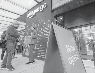  ?? Elaine Thompson photos / Associated Press ?? A customer is handed a compliment­ary shopping bag Monday as he heads into an Amazon Go store in Seattle that has no cashiers. Amazon’s technology charges customers after they leave.