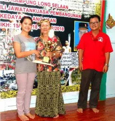  ??  ?? Kulung Punai winner Theresa Nyanding (left) receives her trophy from TK Lucia Paya Kalang, witnessed by Joseph.