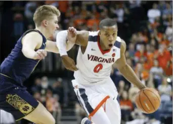  ?? STEVE HELBER — THE ASSOCIATED PRESS ?? Virginia guard Devon Hall (0) drives past Notre Dame guard Rex Pflueger (0) during the second half of an NCAA college basketball game in Charlottes­ville, Va., Saturday. Virginia won the game 62-57.