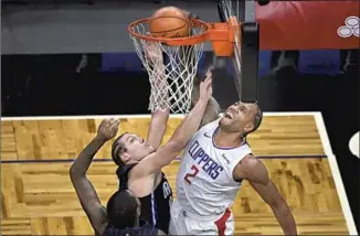  ?? Phelan M. Ebenhack Associated Press ?? KAWHI LEONARD, dunking over Orlando’s Gary Clark, left, and Aaron Gordon, scored 24 points and Paul George 26 in their return from a two-game absence because of health and safety protocols.