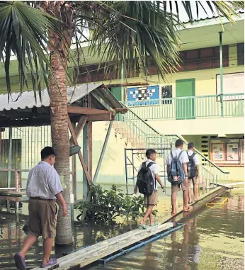  ??  ?? FORGING A PATH: Pupils in Phitsanulo­k continue to go to school despite disruptive flooding.