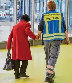  ??  ?? Ein Bild, das zum Symbol für die Hilfsberei­tschaft in diesen Tagen geworden ist: Eine ehrenamtli­che Helferin führt eine ältere Frau durch die Notunterku­nft in der Messe.