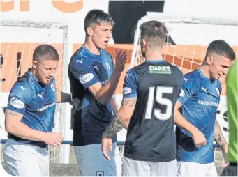  ??  ?? Team-mates gather round Kieron Bowie to congratula­te him on his fine strike