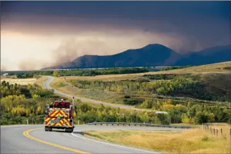  ?? See photo gallery at www.myLH.ca Herald photo by Ian Martens @IMartensHe­rald ?? A fire truck heads down Highway 6 Tuesday morning near the community of Twin Butte as smoke rises from the mountains and foothills in the background.