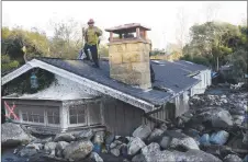  ?? AP PHOTO ?? A firefighte­r stands on the roof of a house submerged in mud and rocks in Montecito, Calif.