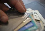  ?? JENNY KANE - THE ASSOCIATED PRESS FILE ?? A man puts his Visa card on a stack of cards for a split check at a restaurant in New Orleans. According to a NerdWallet study $35 is the average fee the country’s largest banks charge customers who overdraw their accounts.