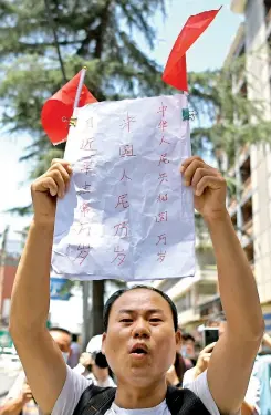  ??  ?? A man holds a banner and shouts “China is great” in front of the US Consulate in Chengdu on Monday. AFP