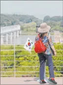  ?? Lee Jin-man The Associated Press ?? A visitor carrying a South Korean flag uses binoculars Tuesday to view the northern side at the Imjingak Pavilion in Paju, South Korea.
