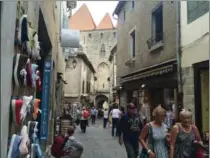  ??  ?? Visitors walk through a gauntlet of tourist shops in the medieval city of Carcassonn­e.