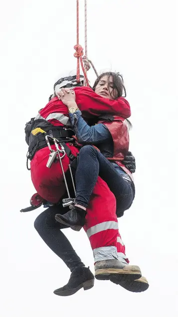  ?? PHOTOS: TYLER ANDERSON / NATIONAL POST ?? A woman who climbed up a crane in downtown Toronto and then made her way down to a dangling hook was rescued by emergency crews early Wednesday, arrested and then taken away in a hospital gurney.