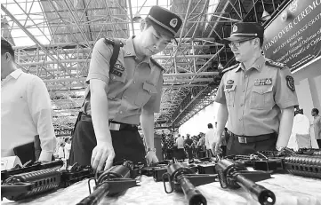  ??  ?? In this file photo, China embassy’s military attaches of the People’s Liberation Army inspect rifles donated by their government to the Philippine military, with a tarpaulen (background right) emblazoned with logos of the Philippine defence department...