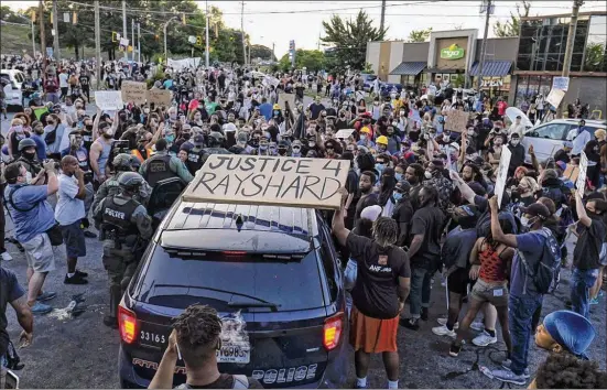  ?? BEN GRAY / FOR THE AJC ?? Police try to disperse demonstrat­ors June 13 at the Wendy’s where Rayshard Brooks was shot to death after a brief struggle with two Atlanta police officers. Video of the confrontat­ion and shooting was widely broadcast on social media, feeding outrage in the community.