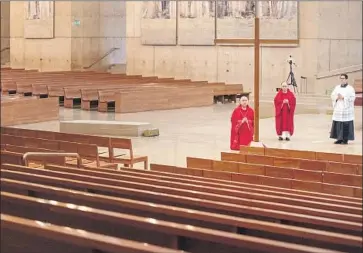  ?? Brian van der Brug Los Angeles Times ?? ARCHBISHOP JOSE GOMEZ kneels during a Good Friday service with Father Brian Nuñez, center, and Father Raymont Medina at Our Lady of the Angels in Los Angeles. The service was held without parishione­rs.