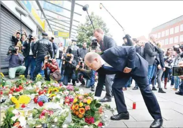  ?? PAUL WEIDENBAUM/DPA/AFP ?? Hamburg’s Mayor Olaf Scholz lays down flowers at a makeshift memorial on Saturday in front of a supermarke­t in Hamburg.