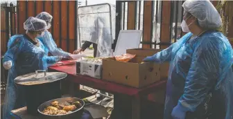  ?? TAMARA MERINO/ BLOOMBERG ?? Social workers serve food in Santiago, Chile, where some communitie­s have revived the dictatorsh­ip-era “olla comun” communal kitchens to provide aid during the pandemic.