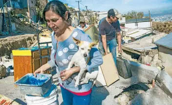  ??  ?? Los habitantes del fraccionam­iento Lomas del Rubí intentan rescatar sus pertenenci­as y poner a salvo a sus mascotas, después de que un deslizamie­nto de tierra causó daños en el vecindario.