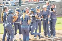  ?? STAFF PHOTO BY TIM BARBER ?? Alexis Trimiar, center, touches home plate after an early solo home run Tuesday as the Soddy-Daisy team crowds in close in their 3-2 District 5-AAA win over visiting Walker Valley.