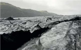  ??  ?? The Myrdalsjok­ull glacier in southern Iceland. Mounds of ash from a 2010 volcanic eruption still coat the giant slab of ice.